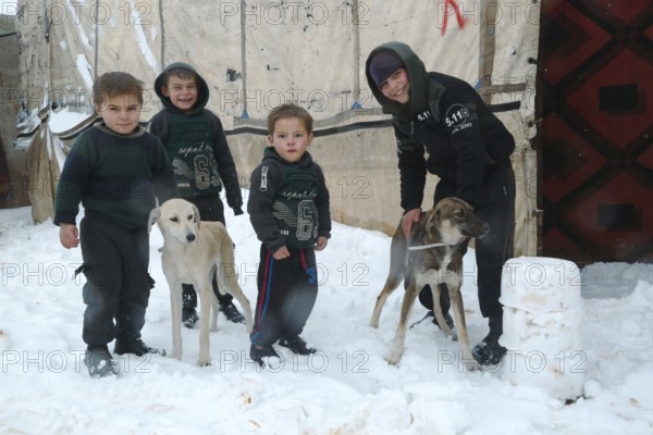 Displaced Syrian families and children living in refugee camps during harsh winter conditions,