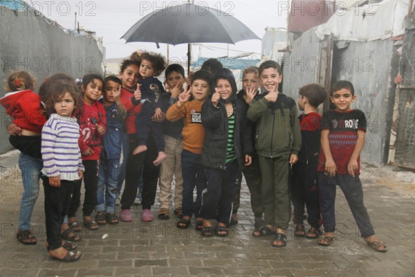 Syrian children inside the refugee camp taking a group photo under the rain on World Children's Day
