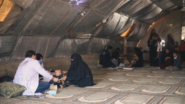 A doctor examining a woman inside a mobile medical point dedicated to treating Syrian refugees.