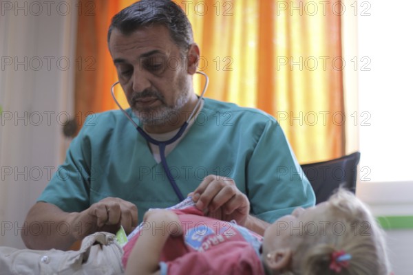A doctor examining a displaced Syrian child inside a mobile clinic at a refugee camp. Aleppo, Syria