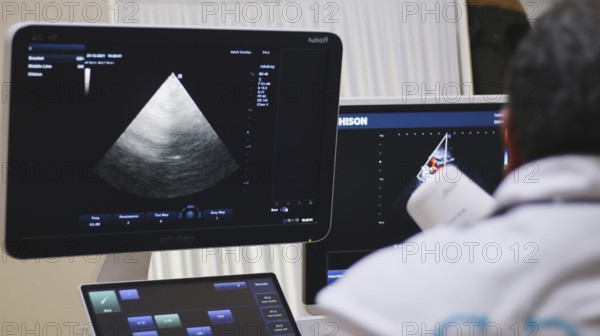 A gynecologist performing an ultrasound examination for an elderly displaced woman inside a mobile