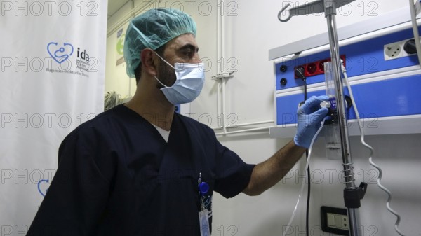 A doctor adjusting the oxygen ventilator settings for a patient inside the intensive care unit