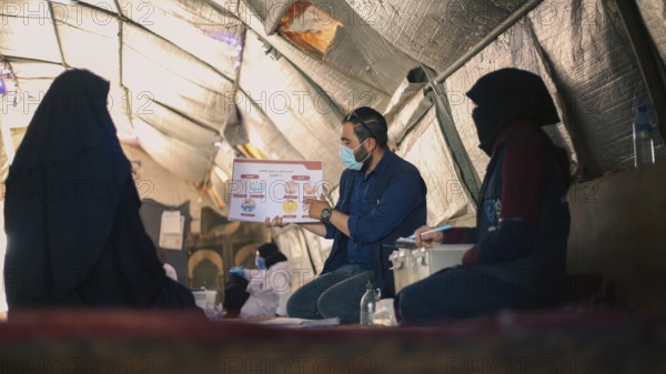 A community health worker giving instructions to refugees on how to deal with the cholera outbreak