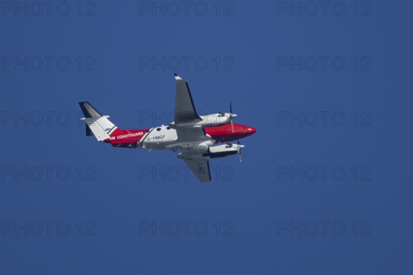 Beech King Air 350 light aircraft of the UK HM Coastguard flying in a blue sky, England, United