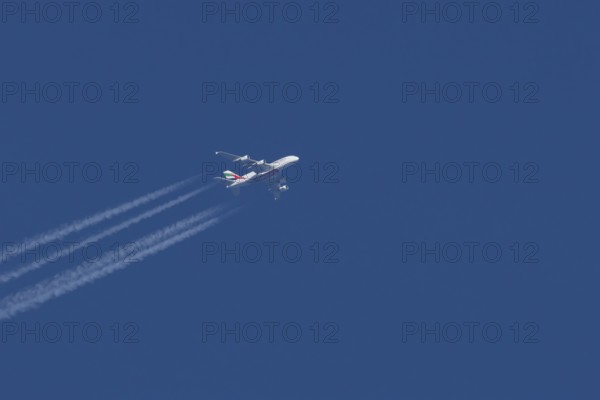 Airbus A380 jet passenger aircraft of Emirates airlines with a vapour trail or contrail flying in a