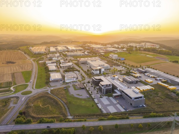 Industrial park at sunset, with symmetrical streets and a mixture of fields and buildings,
