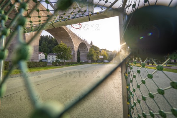 Playground with basketball hoop and a large bridge in the evening sunlight, Nagold, Calw district,