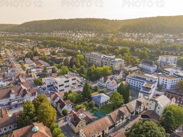 Urban environment with residential buildings and many trees, rising hills in the background in