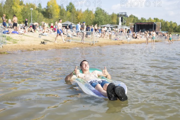 Festival visitor Sven lies on an air mattress in Lake Störmthal at the Highfield Festival on