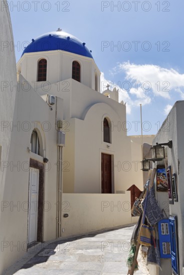 Orthodox church with blue dome in a narrow alley, shopping in the old town, Oia, Thira, Santorini,
