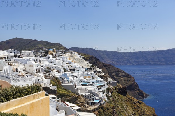 White and colourfully painted holiday homes, orthodox church with blue dome on the edge of the