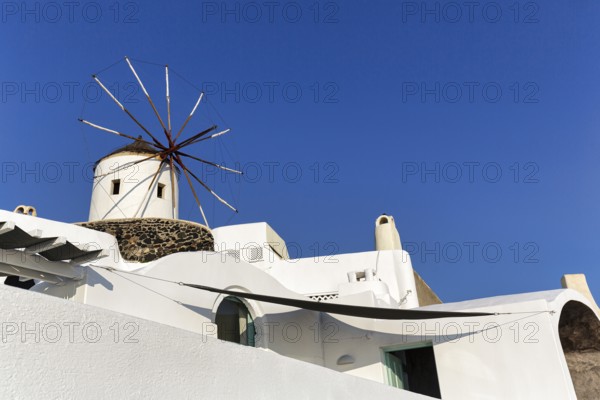 White windmill, typical holiday home, blue sky, sunny weather, text free space, Oia, Thira,