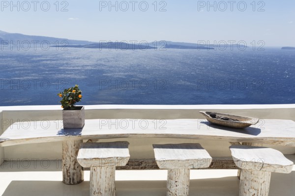 Wooden table on a white terrace by the sea, view of the caldera, Oia, Thira, Santorini, Cyclades,