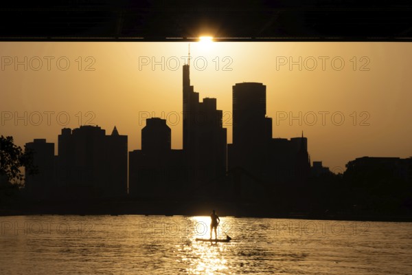 The evening sun stands over the Frankfurt banking skyline while paddlers and rowers navigate the
