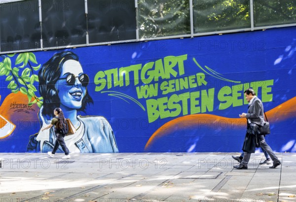 People on the move in the Königstraße pedestrian zone in Stuttgart. Construction fence with the