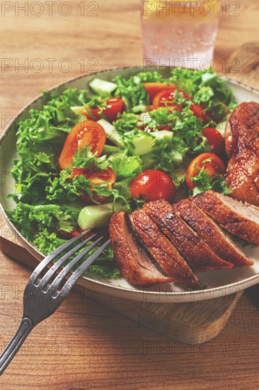 Delicious grilled duck breast served with fresh garden salad and cherry tomatoes at a rustic dining