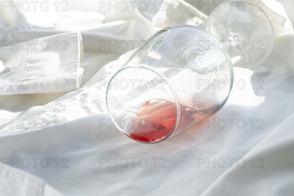 Glass, with pink wine, spilled on a white shirt, close-up, selective focus, no people, concept, top