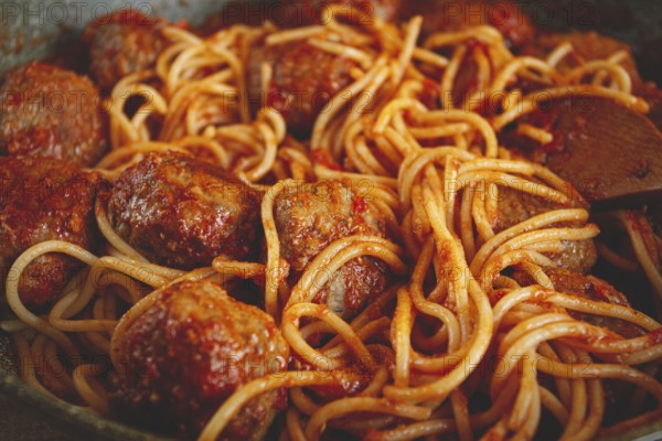 Spaghetti with meatballs, in tomato sauce, cooking in a frying pan, no people, homemade