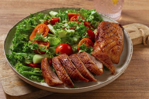 Delicious grilled duck breast served with fresh garden salad and cherry tomatoes at a rustic dining