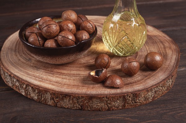 Bottle of macadamia oil, on a wooden board, with macadamia nuts, wooden background, selective
