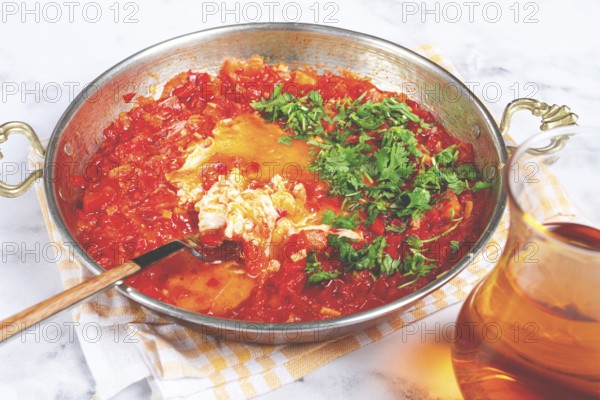 Traditional Turkish dish, scrambled eggs with tomatoes, Menemen, with herbs, in a frying pan,