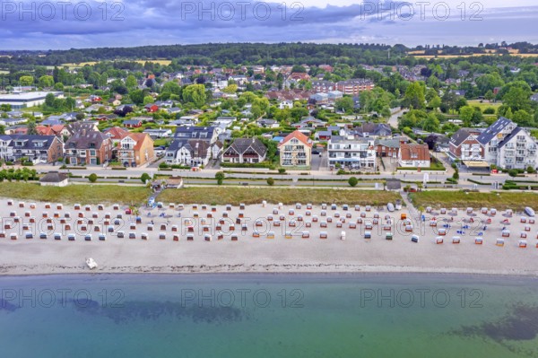 Aerial view over sandy beach with roofed wicker beach chairs and seaside resort Haffkrug along the