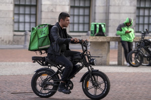 Bicycle traffic in Groningen, Uber Eats, courier driver with e-bike in moped style, fatbike,