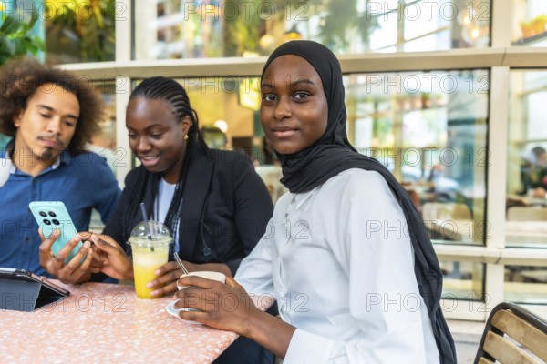 Diverse group of young friends at a cafe laughing and sharing content on a smartphone, enjoying