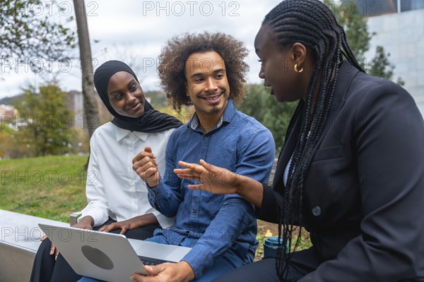 Diverse colleagues discussing and brainstorming ideas while working on a laptop together,