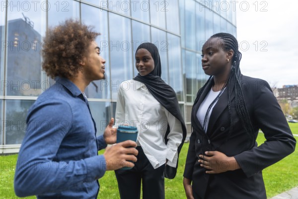 Diverse business professionals standing outdoors, engaging in an informal discussion during a