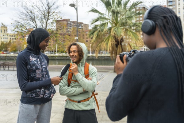 Content creators filming an outdoor interview with a smiling man, capturing diverse perspectives