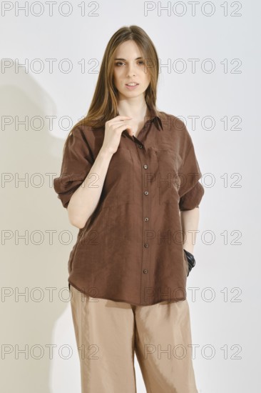 A woman stands confidently, wearing a trendy brown shirt and light-colored pants, perfect for