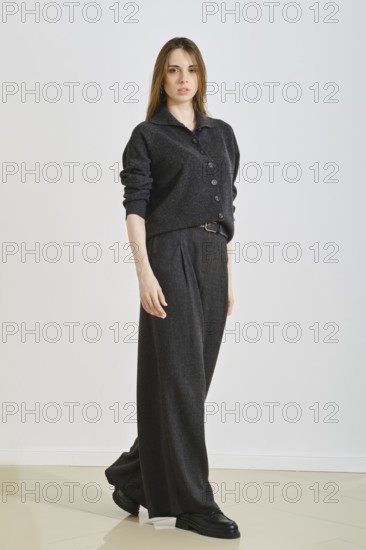 A woman showcases a stylish black ensemble featuring a button-up top and wide-legged pants.