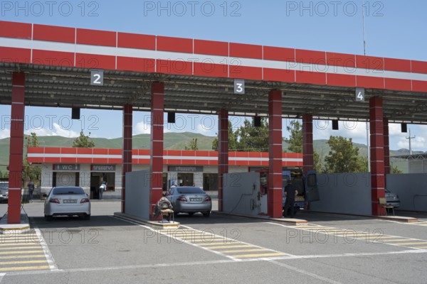 Gas station with red roof, numbered passages and parked cars, gas filling station, Sewan,
