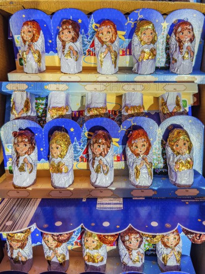 Chocolate Christmas angel in musical instruments printed on colorful staniol paper on a retail