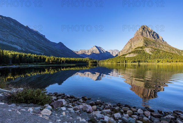 240831_066 Rippled reflection of the mountains on the calm waters of Lake Josephine in Glacier