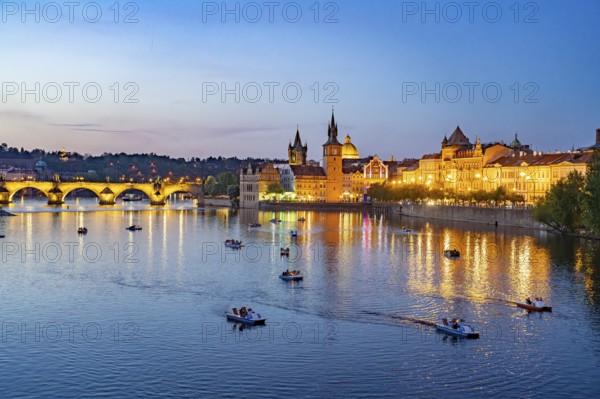 Vltava embankment with Old Town Water Tower, Novotný Bridge and Charles Bridge at dusk, Prague,