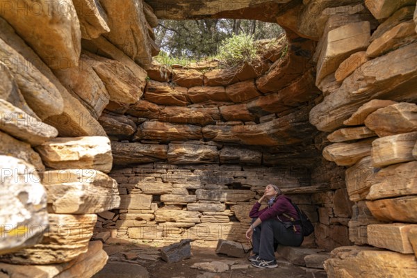 Tourist sitting in the Palli-Lakka Drakospita dragon house near Styra, island of Euboea or Evia,