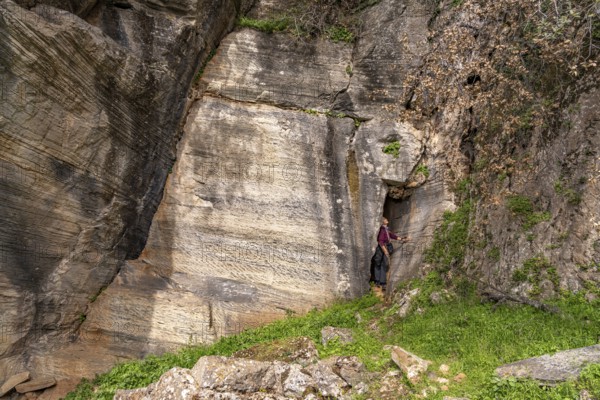 Tourist in the quarry near the prehistoric Palli-Lakka dragon houses Drakospita near Styra, island
