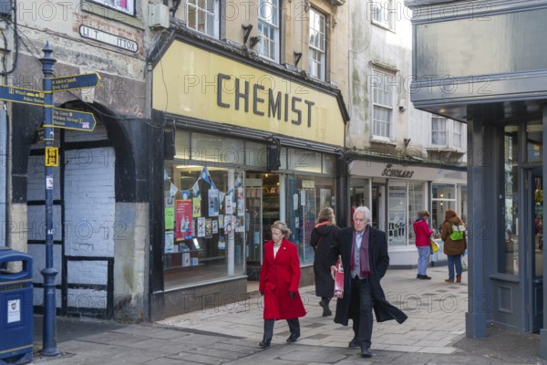 Shops and shoppers in Little Brittox street, Devizes, Wiltshire, England, UK traditional Chemist