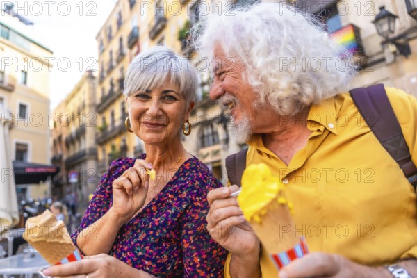 Happy mature couple smiling together while eating ice cream cones, experiencing leisure and love