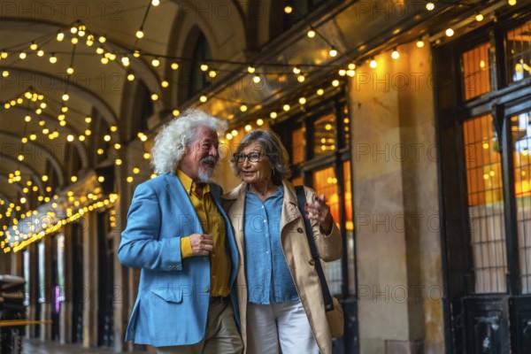 Senior couple walking arm in arm under string lights, happily talking while enjoying an evening out