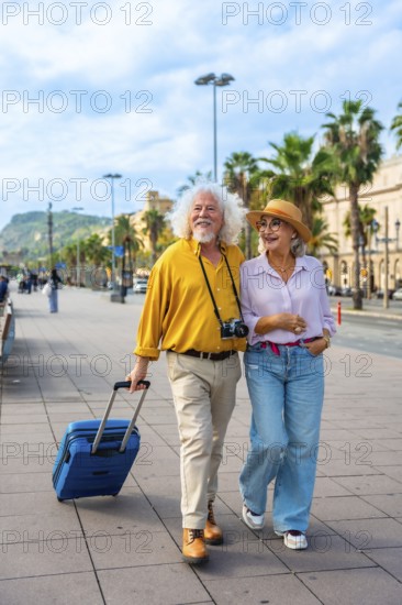 Smiling senior couple embracing a happy retirement, walking together with their luggage through a