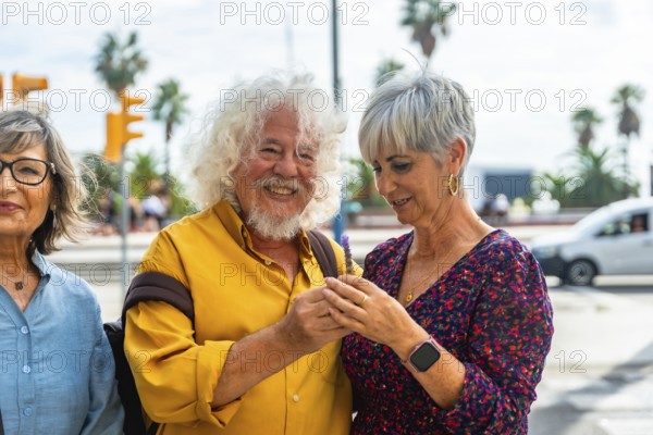 Senior couple embracing on a sunny city street, smiling and looking at a smartphone while enjoying