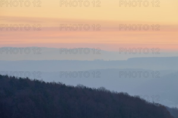 Pastel-colored silhouettes of hills and trees at sunset convey a peaceful atmosphere, Seckmauern,
