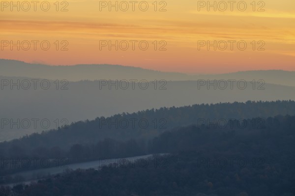 Gentle hills in fog at a warm sunset create a peaceful natural landscape, Seckmauern, Lützelbach,