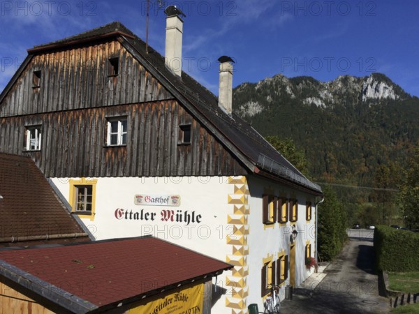 View of side view of Gasthof Ettaler Mühle in a historic two-storey baroque half-hipped roof dating