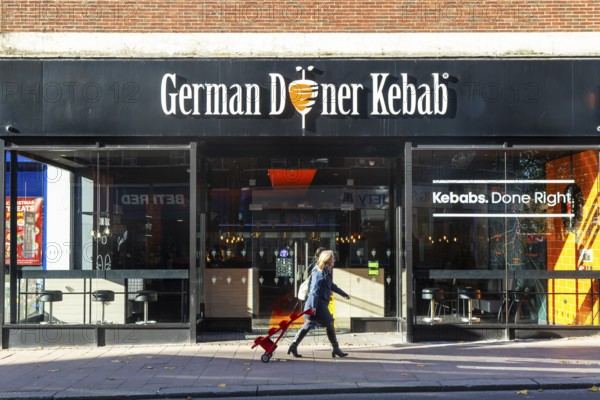 Person passing GDK German Doner Kebab takeaway restaurant in city centre, Exeter, Devon, England,