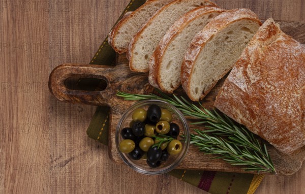 Sliced ciabatta, on a chopping board, with rosemary and olives, Italian bread, close-up, Italian