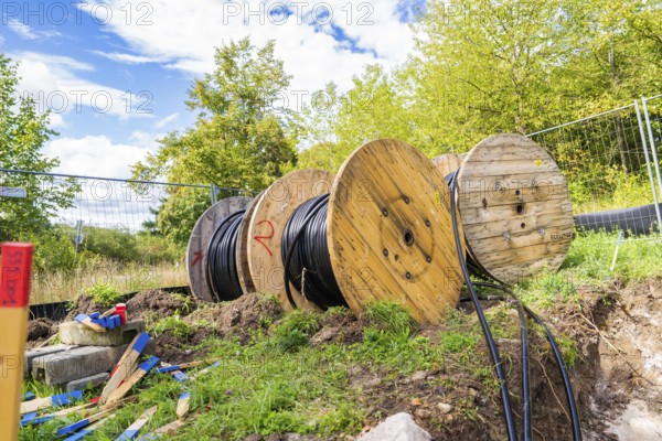 Several large cable drums with cables on a construction site in a green area, Bau PV